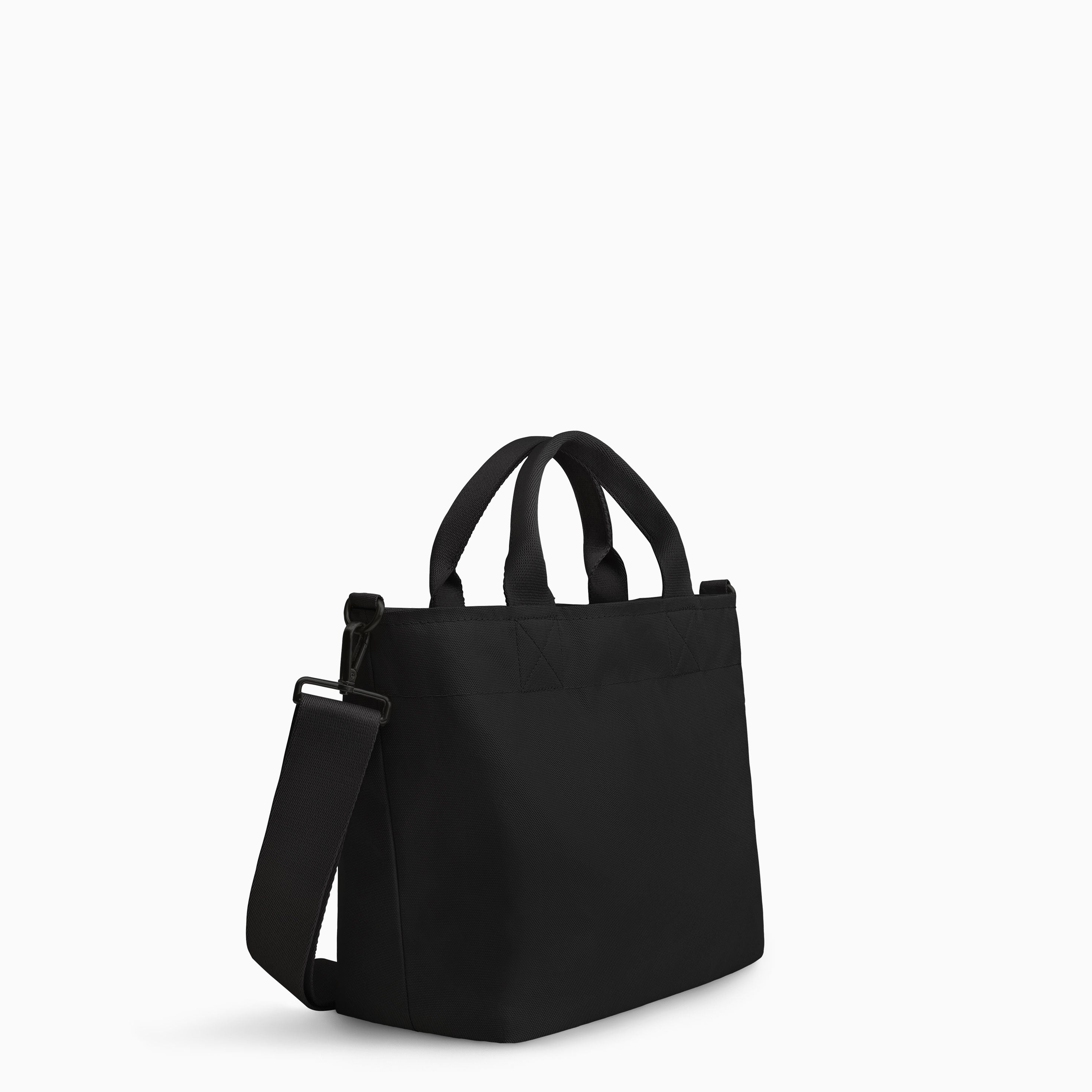Canvelle Zip Crossbody Tote in small black canvas with black hardware - Angled view showing depth and side profile.