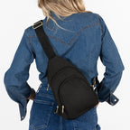 Woman wearing medium Canvelle City Sling Bag in black canvas across the back over a denim shirt to demonstrate everyday size and hands-free fit.