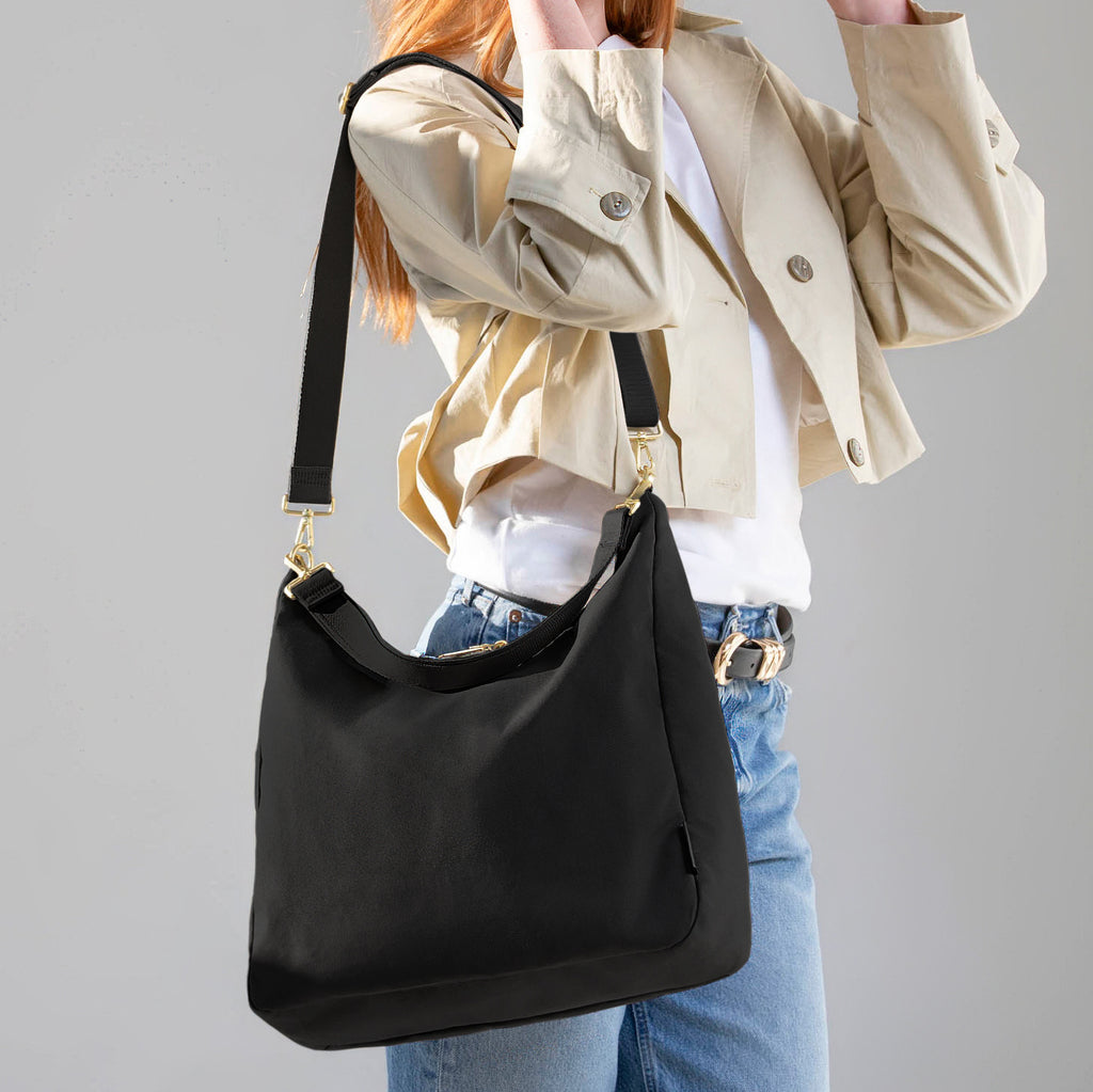 Woman wearing the large black Canvelle Hobo Handbag on the shoulder to show everyday size and casual style.
