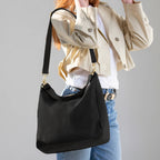 Woman wearing the large black Canvelle Hobo Handbag on the shoulder to show everyday size and casual style.