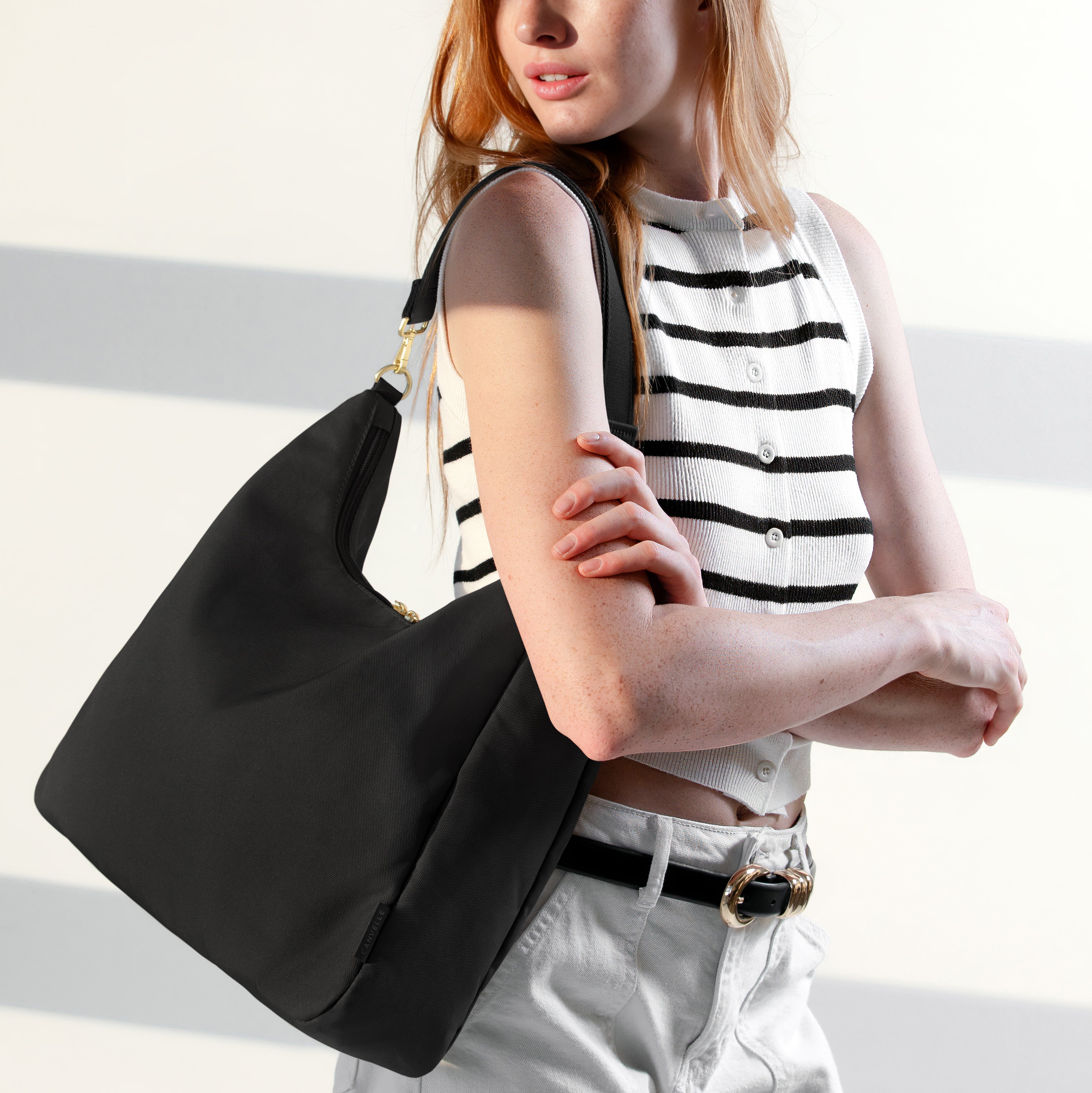 Woman wearing the large black Canvelle Hobo Handbag crossbody with the long adjustable strap to show hands-free style.