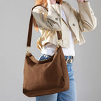 Woman wearing the large brown Canvelle Hobo Handbag on the shoulder to show everyday size and casual style.
