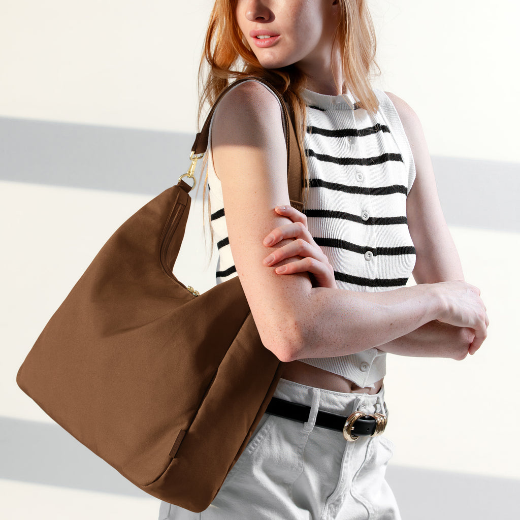 Woman wearing the large brown Canvelle Hobo Handbag crossbody with the long adjustable strap to show hands-free style.