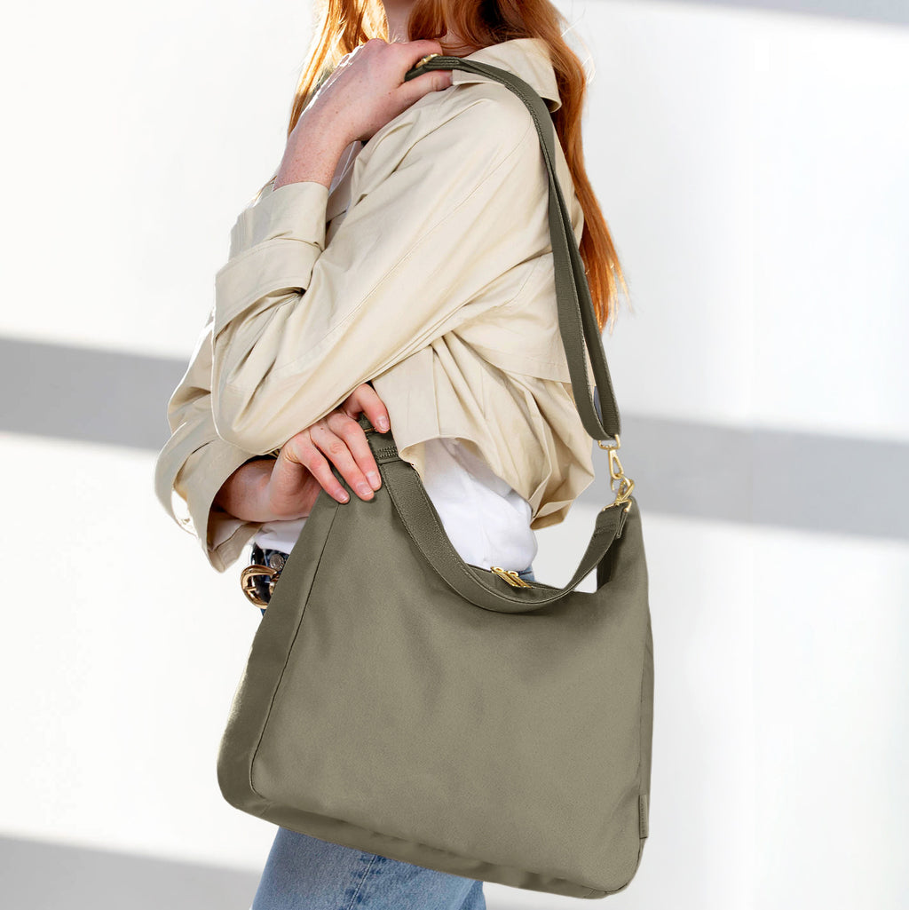 Woman wearing the large olive Canvelle Hobo Handbag on the shoulder to show everyday size and casual style.