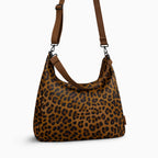 Canvelle Hobo Handbag in large brown leopard print canvas - Angled view with crossbody strap showing depth and side profile.