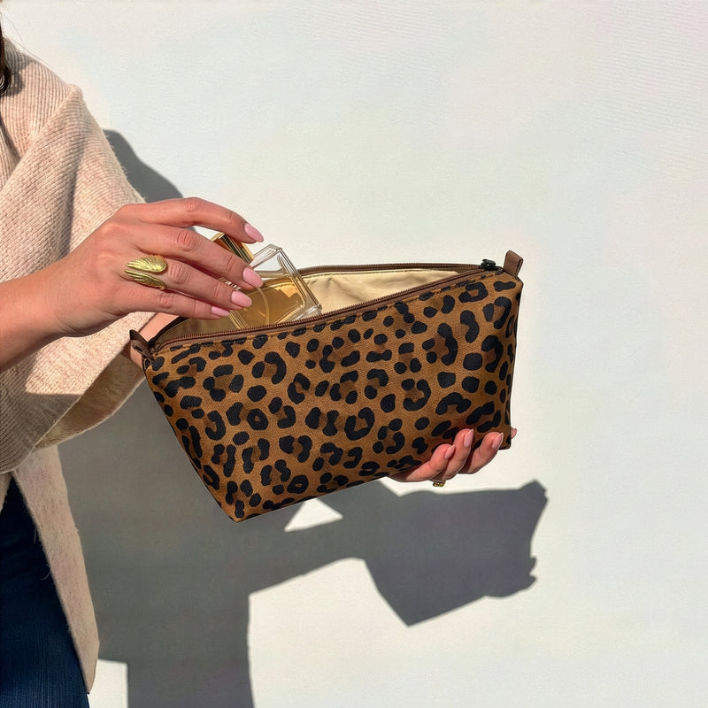 Open medium brown leopard Canvelle Toiletry Pouch packed with full-size toiletries and skincare.