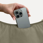Phone sliding into the exterior back slip pocket of the large olive Canvelle Hobo Handbag.