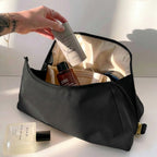 Woman packing large black Canvelle Toiletry Bag with travel essentials like Salt & Stone deodorant to demonstrate capacity and wide opening.
