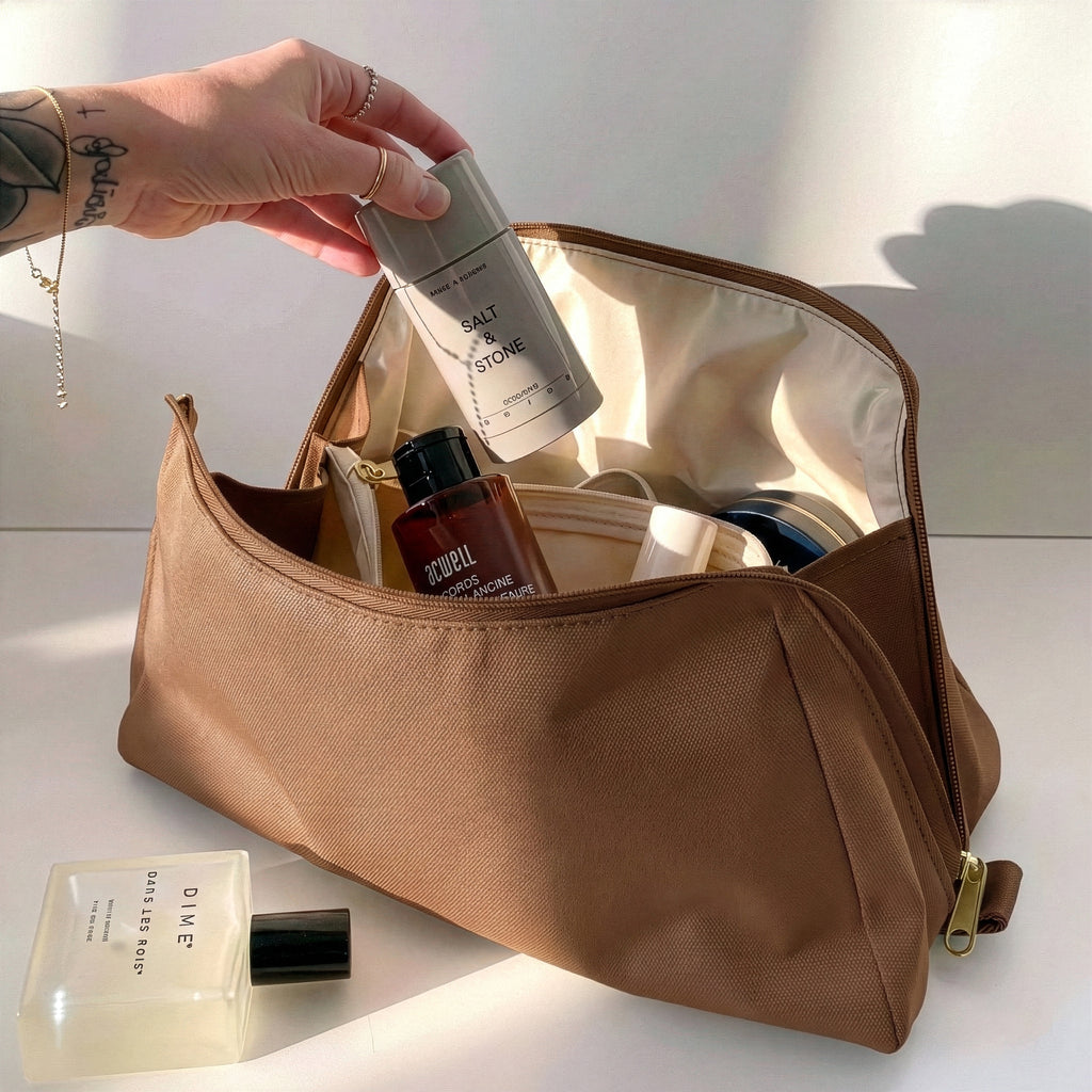 Woman packing large brown Canvelle Toiletry Bag with travel essentials like Salt & Stone deodorant to demonstrate capacity and wide opening.