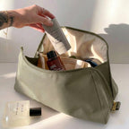 Woman packing large olive green Canvelle Toiletry Bag with travel essentials like Salt & Stone deodorant to demonstrate capacity and wide opening.