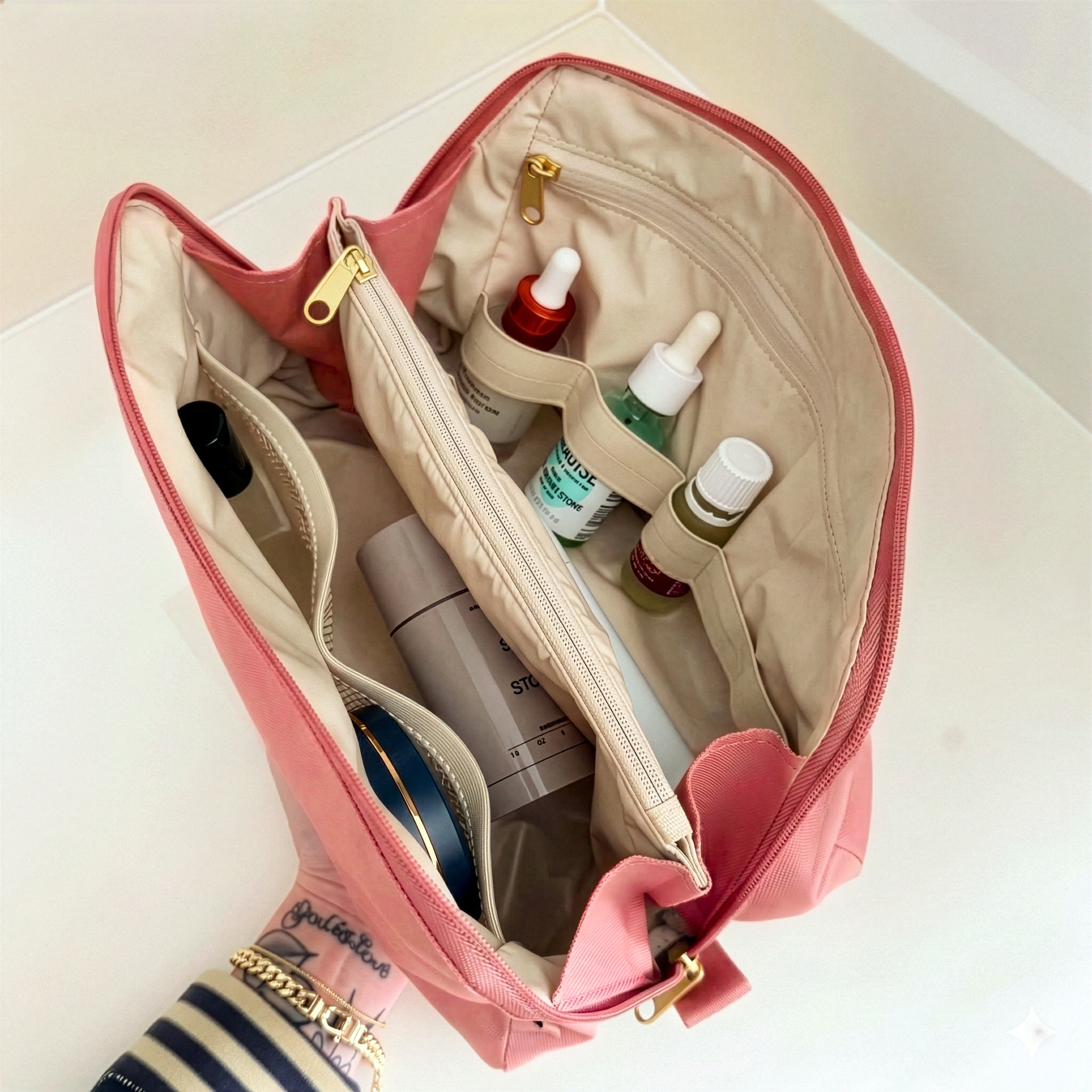 Top-down view of organized large pink Canvelle Toiletry Bag holding skincare serums, Dime perfume, and toiletries in upright elastic loops and dividers.