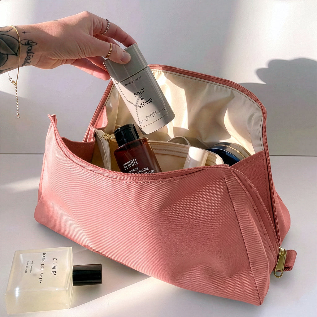 Woman packing large pink Canvelle Toiletry Bag with travel essentials like Salt & Stone deodorant to demonstrate capacity and wide opening.